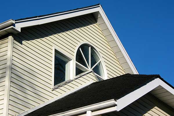 Close up of the second floor of a mid-class home with beige vinyl siding
